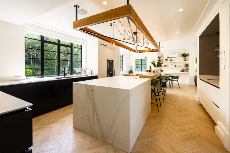 A marble kitchen island under a timber beam light fitting