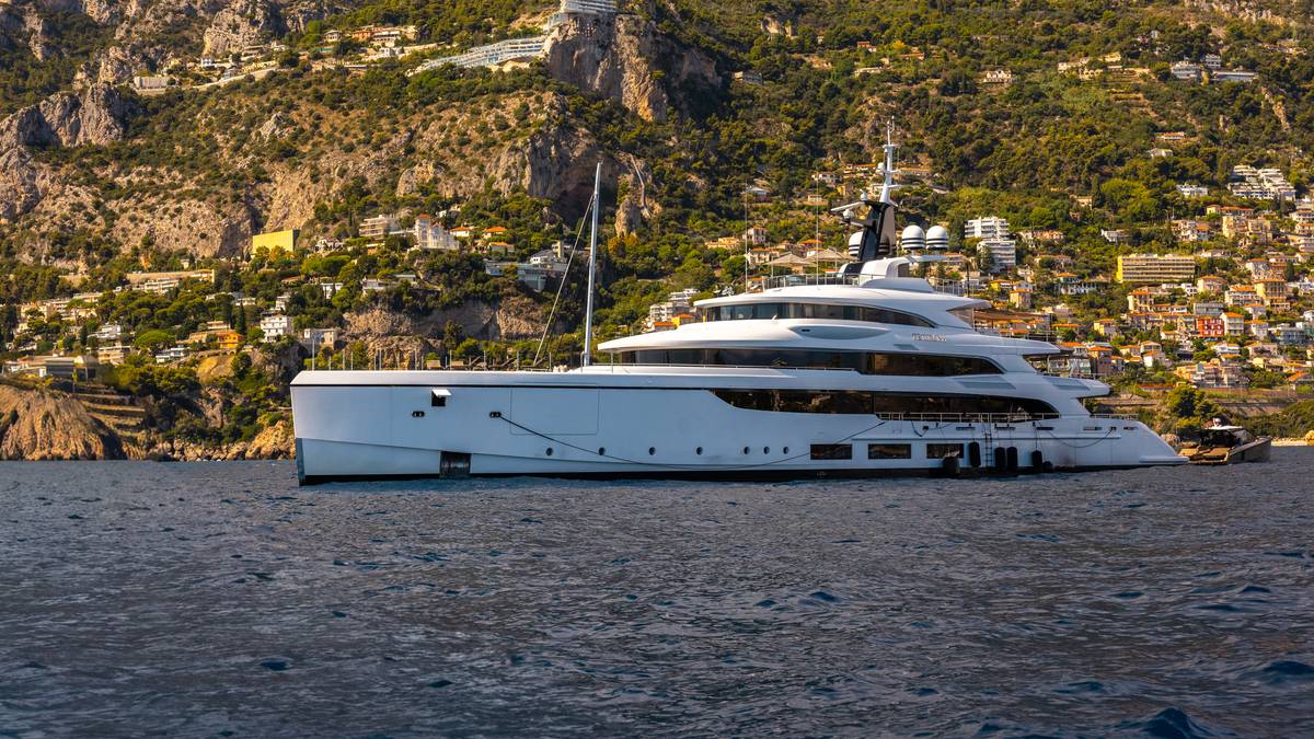 A superyacht at anchor against the Monaco coastline at golden hour