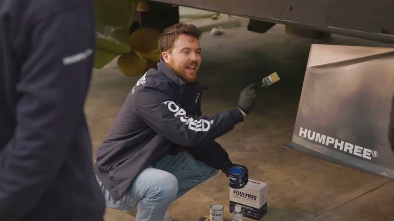 A technician applying coating beside a Humphree fin in a boatyard