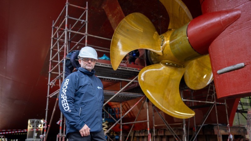A Propspeed technician in front of a ship&rsquo;s propeller in dry dock