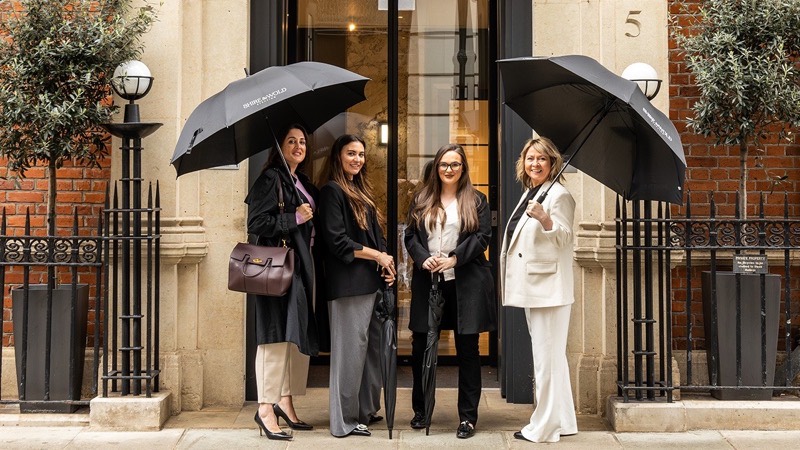 Four recruiters outside a townhouse office under branded umbrellas